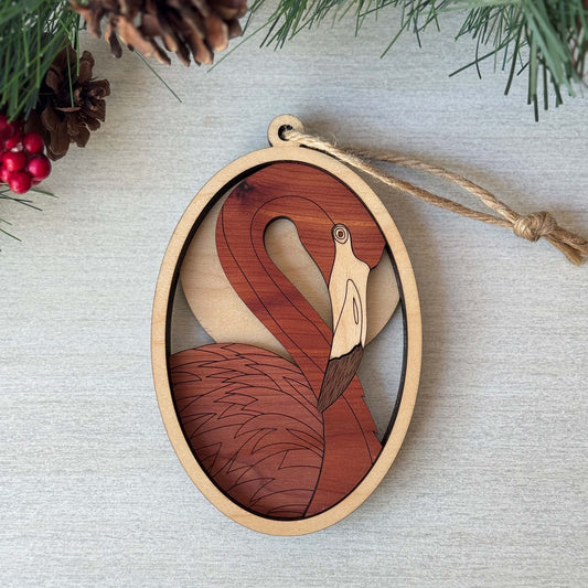 Wooden flamingo ornament on a light gray background with Christmas decorations.