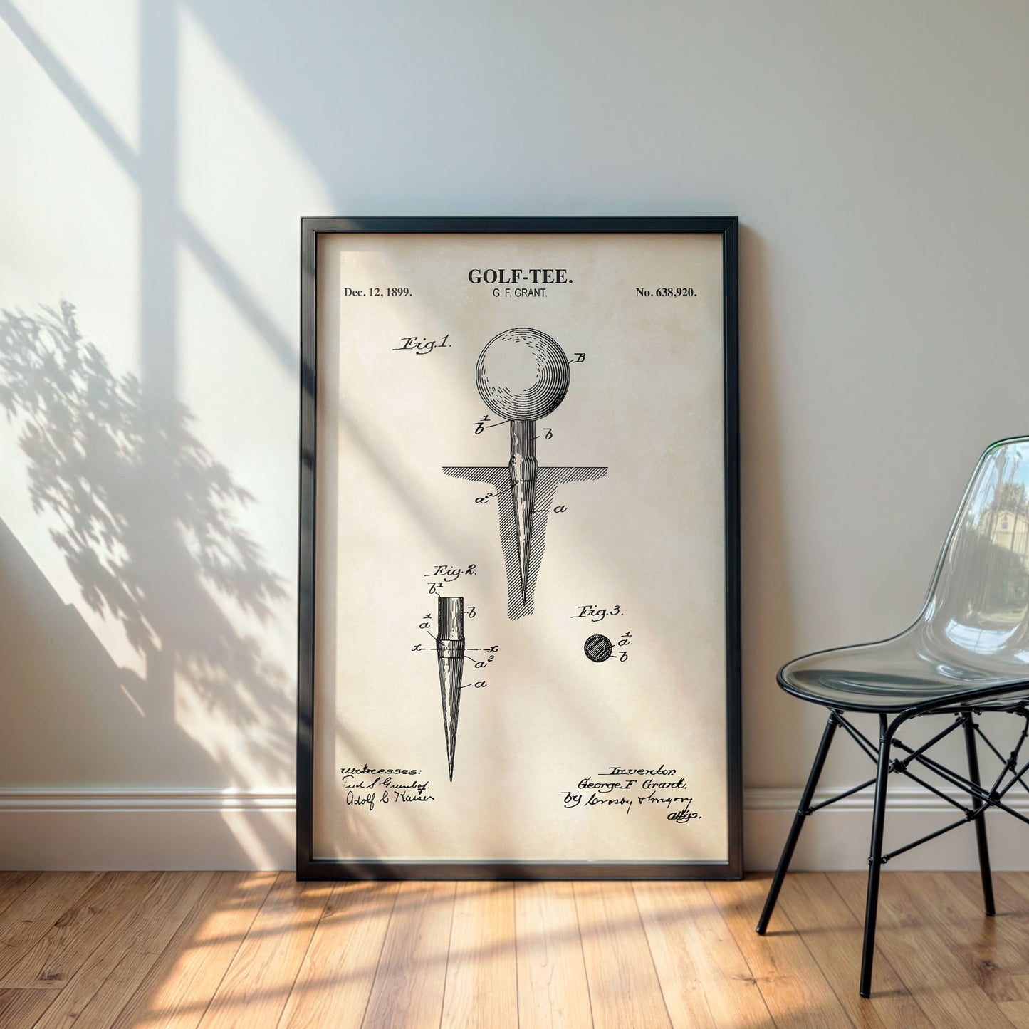 Framed golf tee patent print on a wall with a chair and plant in the background