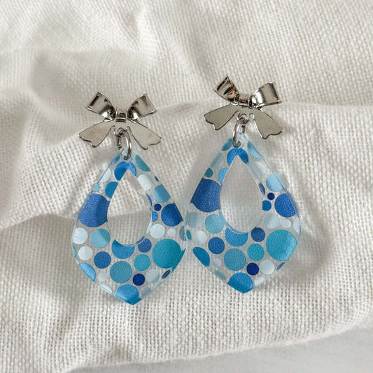 Teardrop-shaped earrings with blue pattern on a light fabric background