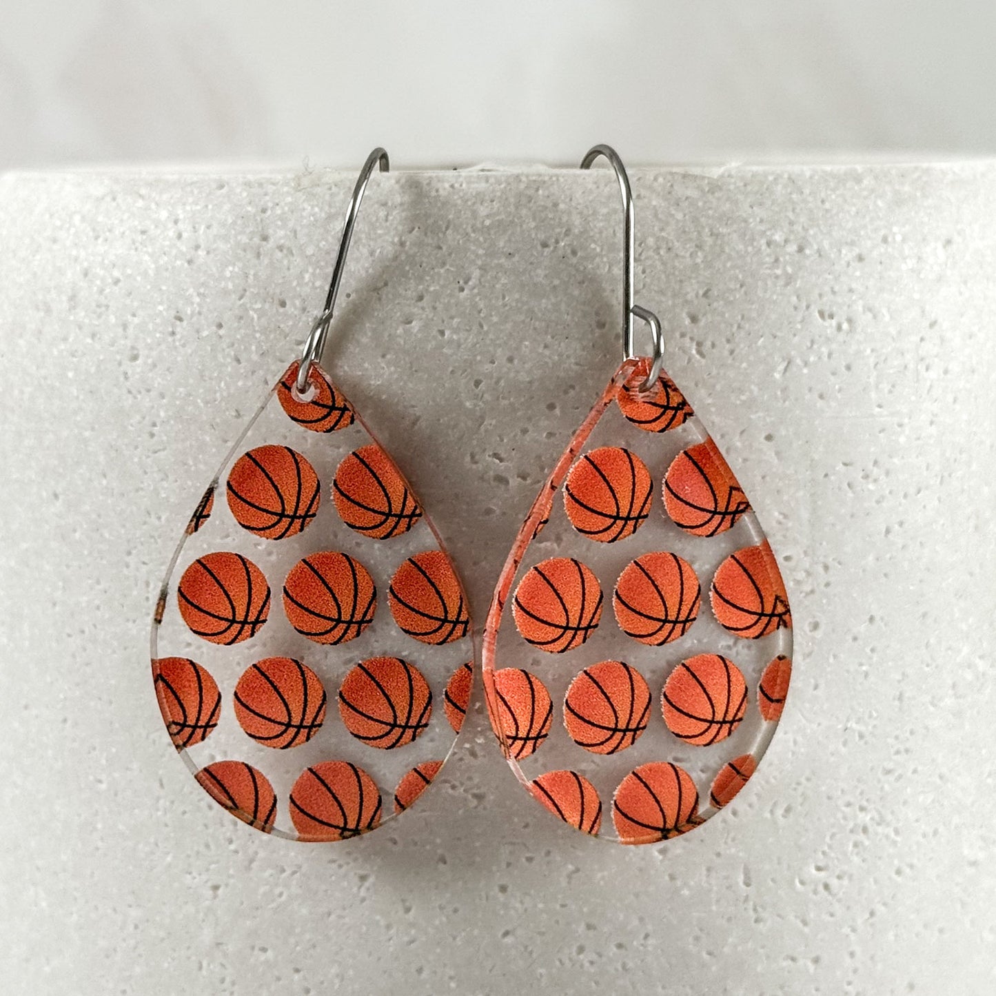 Teardrop-shaped earrings with basketball pattern on a light gray background