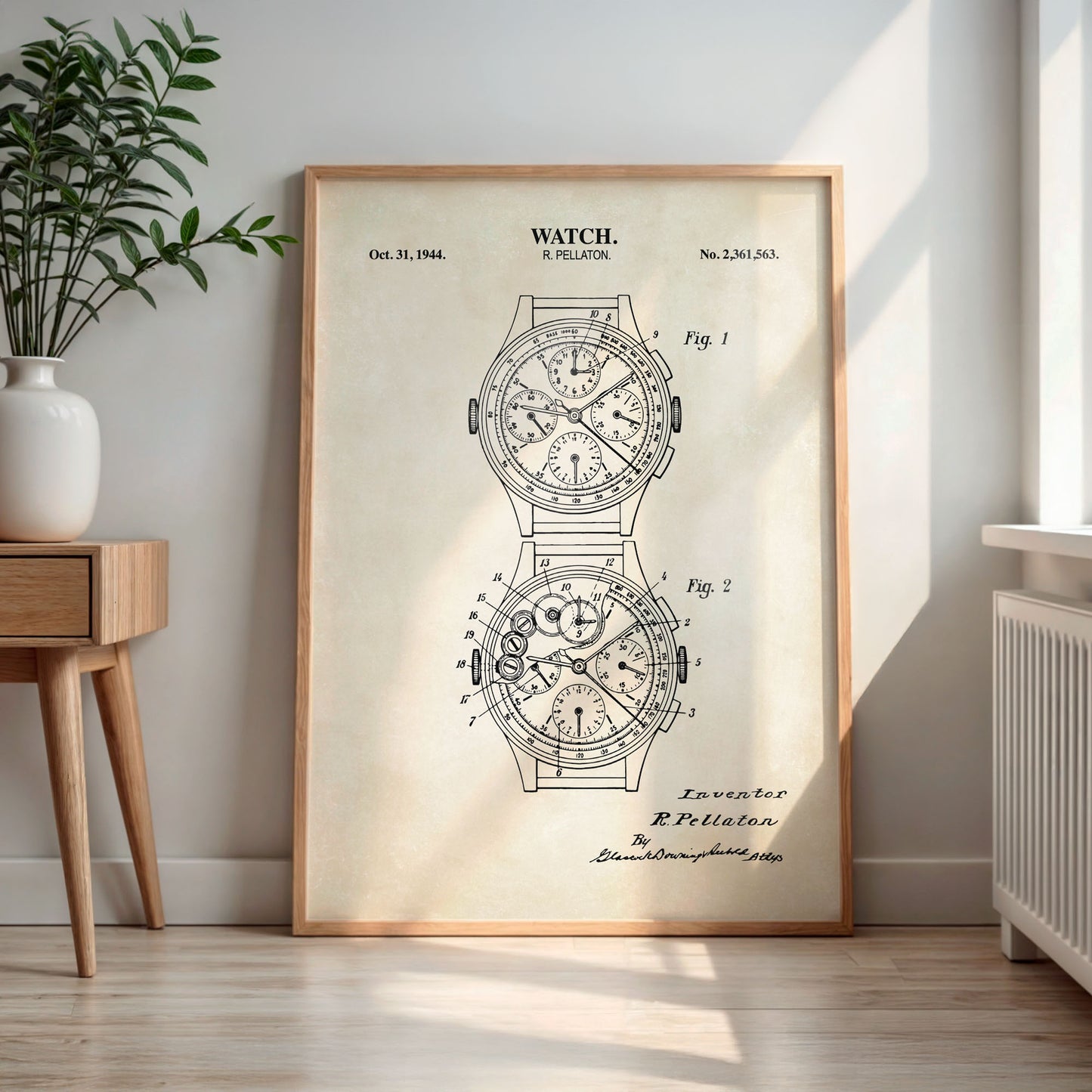 Framed watch patent print on a wall in a room with a plant and wooden side table.