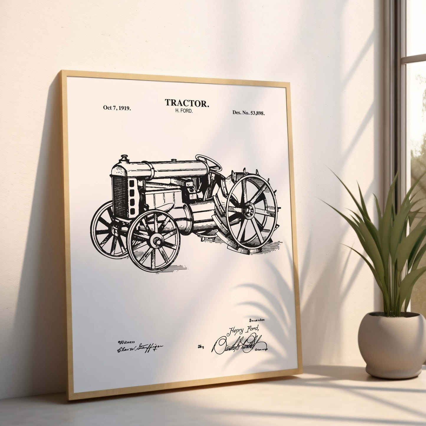 Framed poster of a vintage tractor design on a light surface with a plant in the background