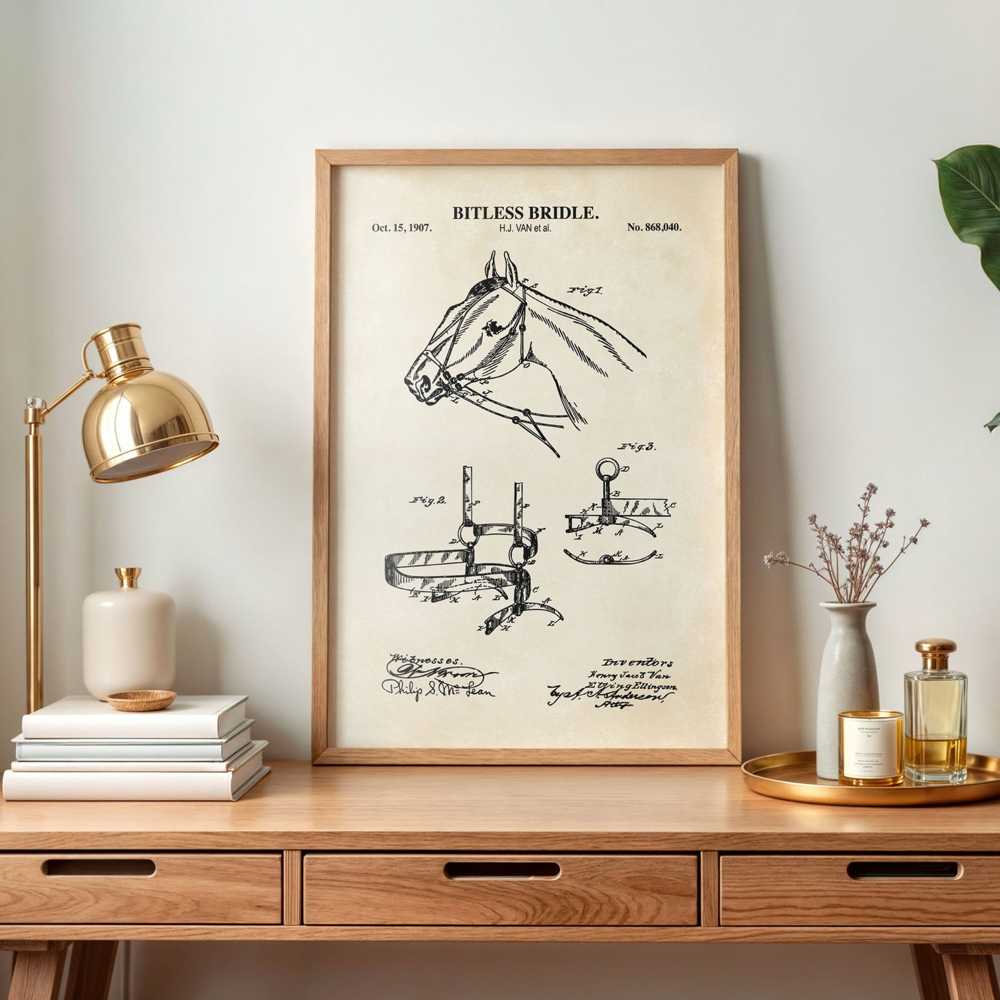 Framed patent print of a bitless bridle on a wooden desk with decorative items.