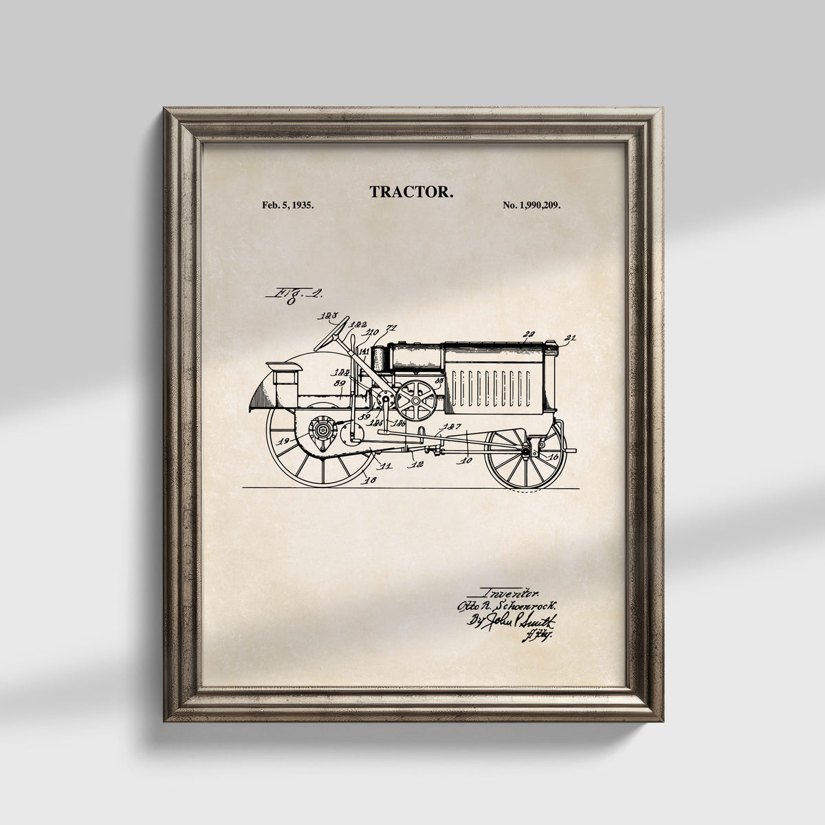 Framed vintage tractor patent art print with a detailed black line drawing on an aged beige background, shown in a distressed silver frame against a light gray wall.