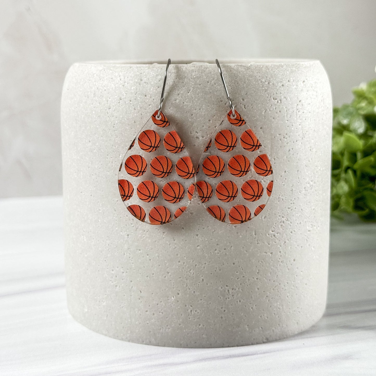 Basketball patterned earrings on a white cylindrical container with a light background