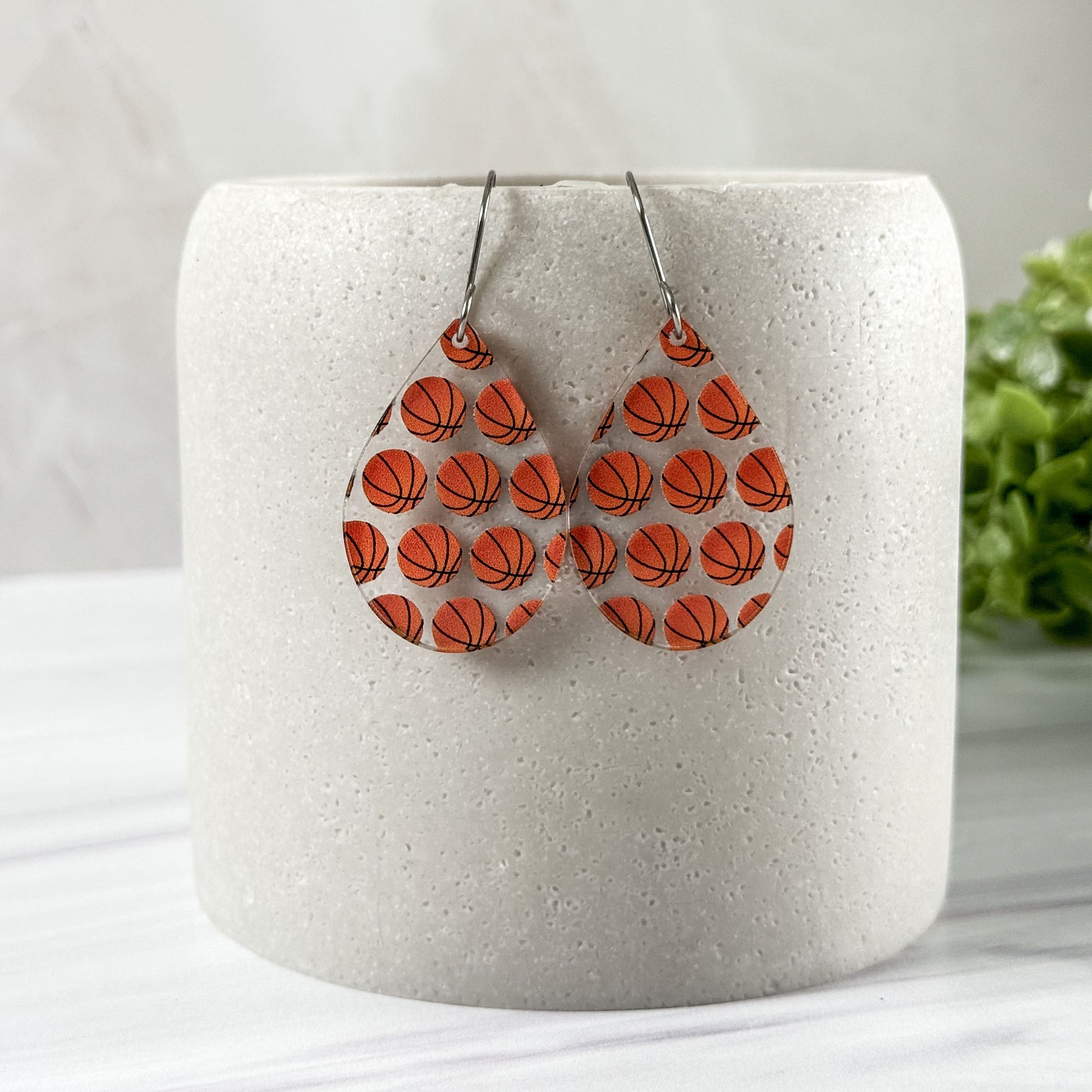 Basketball patterned earrings on a white cylindrical container with a light background