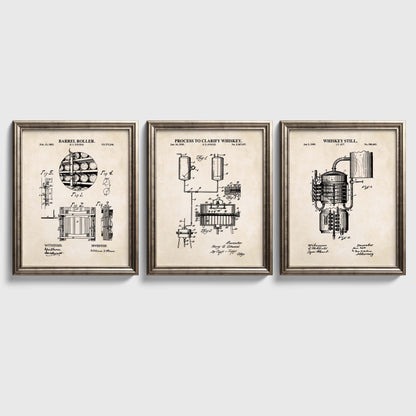 Three framed prints on a white wall, each displaying technical drawings of whiskey-making equipment.