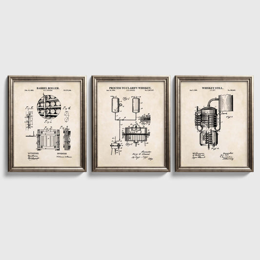 Three framed prints on a white wall, each displaying technical drawings of whiskey-making equipment.