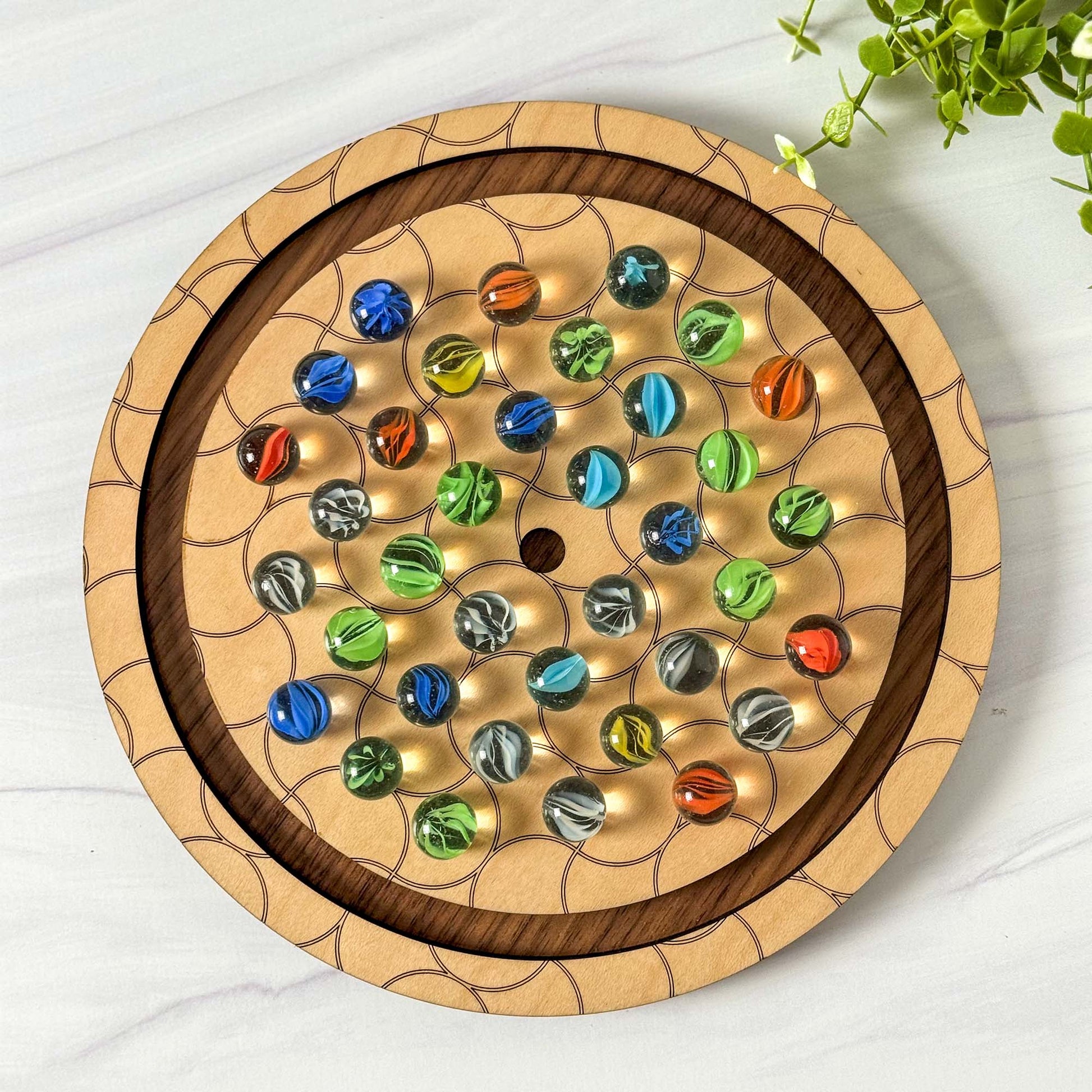 Wooden marble solitaire game with colorful marbles on a white surface