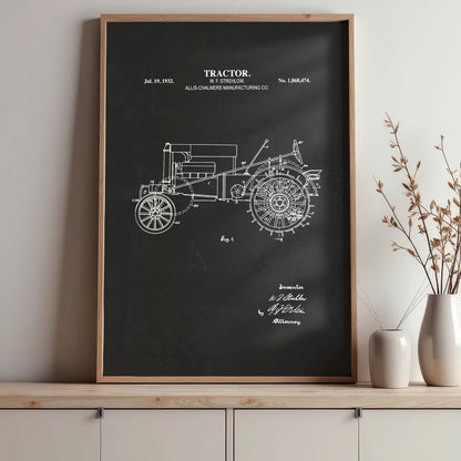 Framed tractor blueprint on a wall above a wooden shelf with decorative items.