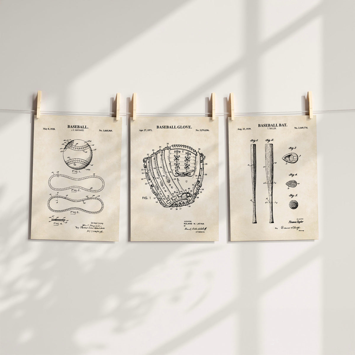Three vintage-style baseball patent art prints are clipped to a string against a white wall, with soft window shadows cast across the scene.