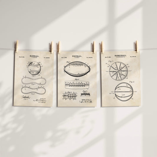 Three vintage-style patent art prints of sports equipment (baseball, football, basketball) hanging from a string with wooden clothespins against a white wall with soft shadow overlays.