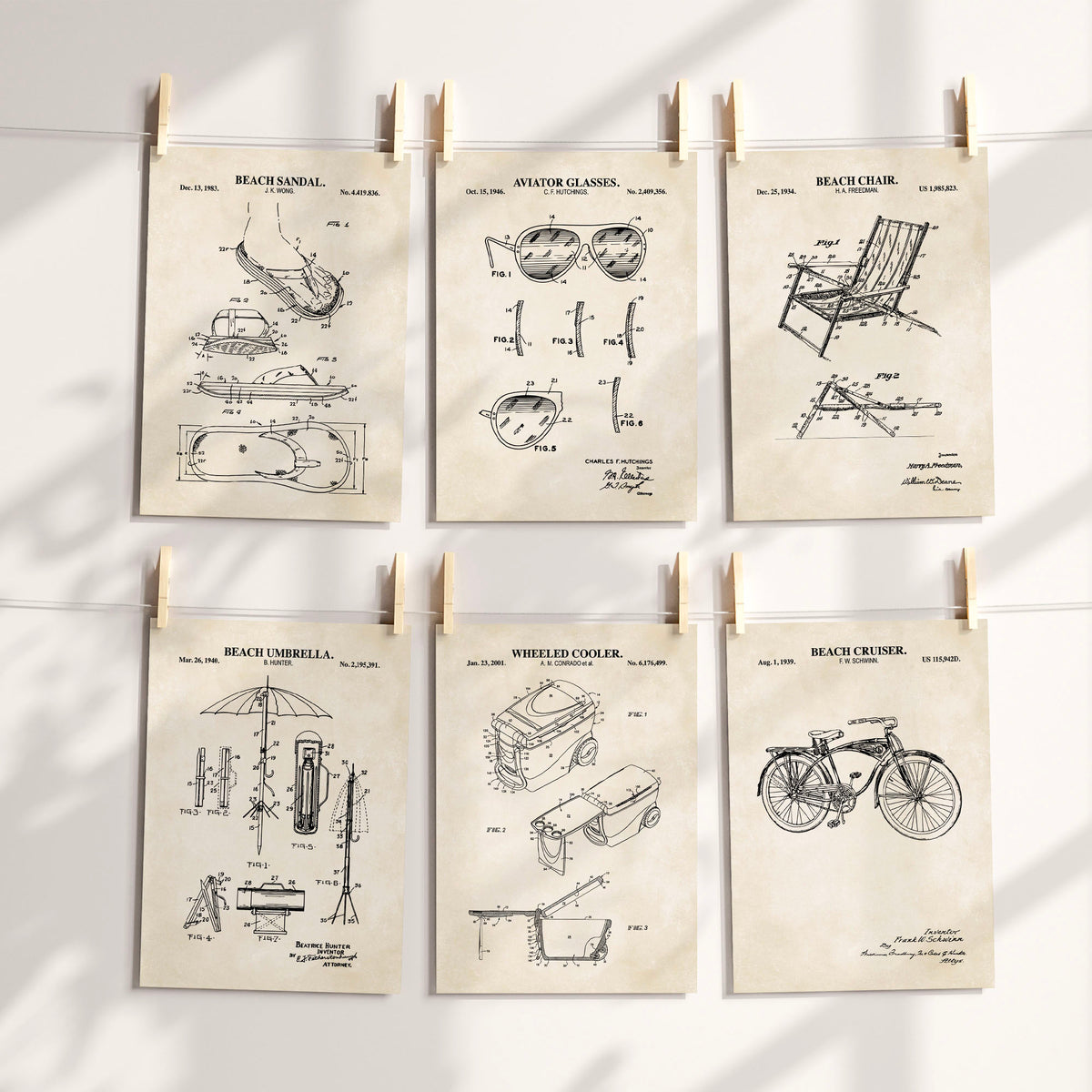 Six vintage-style beach-themed patent art prints are clipped to a white string against a sunlit wall. The prints feature black technical drawings and text for a beach sandal, aviator glasses, beach chair, beach umbrella, wheeled cooler, and beach cruiser, all on warm cream paper.