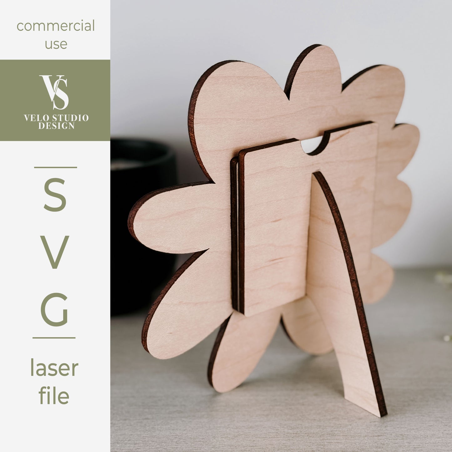 A wooden stand made from laser-cut layered wood pieces, shown on a tabletop with a blurred background. A vertical sidebar on the left reads 'commercial use', 'VELO STUDIO DESIGN', and 'SVG laser file'.
