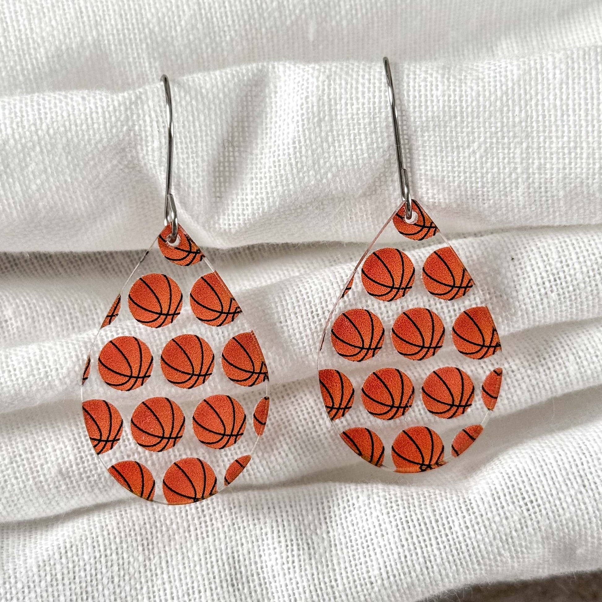 Basketball patterned earrings on a white fabric background