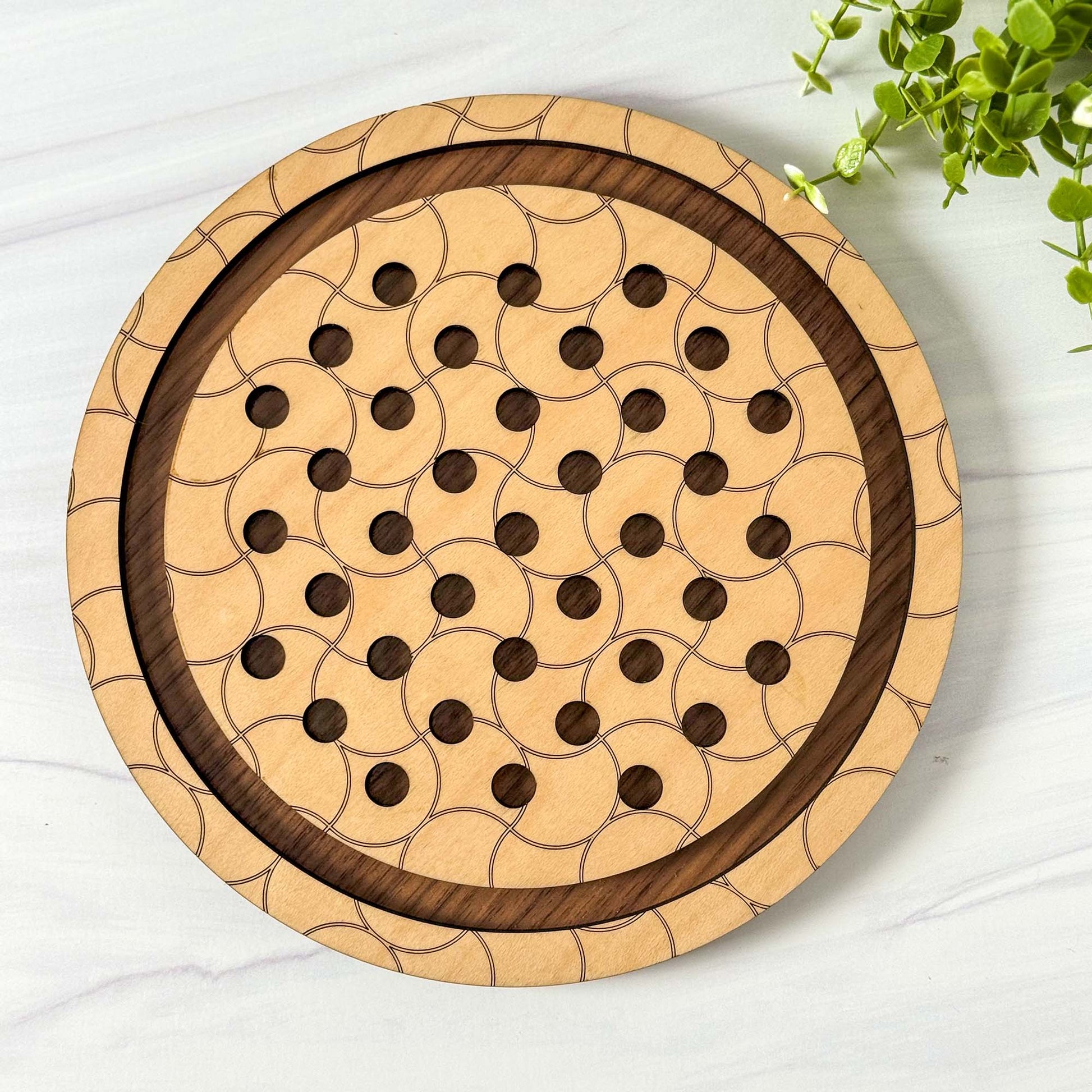 Wooden marble solitaire board with a geometric design on a white surface