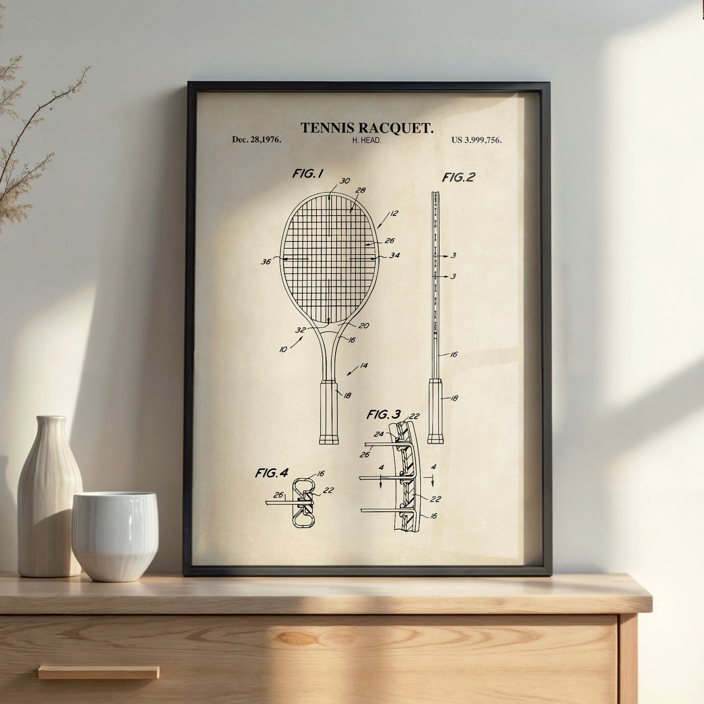 Framed tennis racquet patent print on a wooden surface with decorative items.