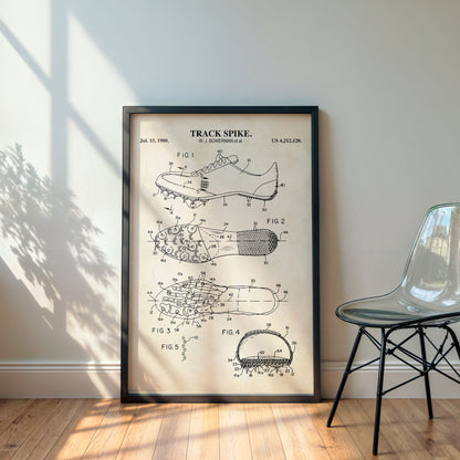 Framed poster of a track spike patent on a wall with a chair and plant in the background