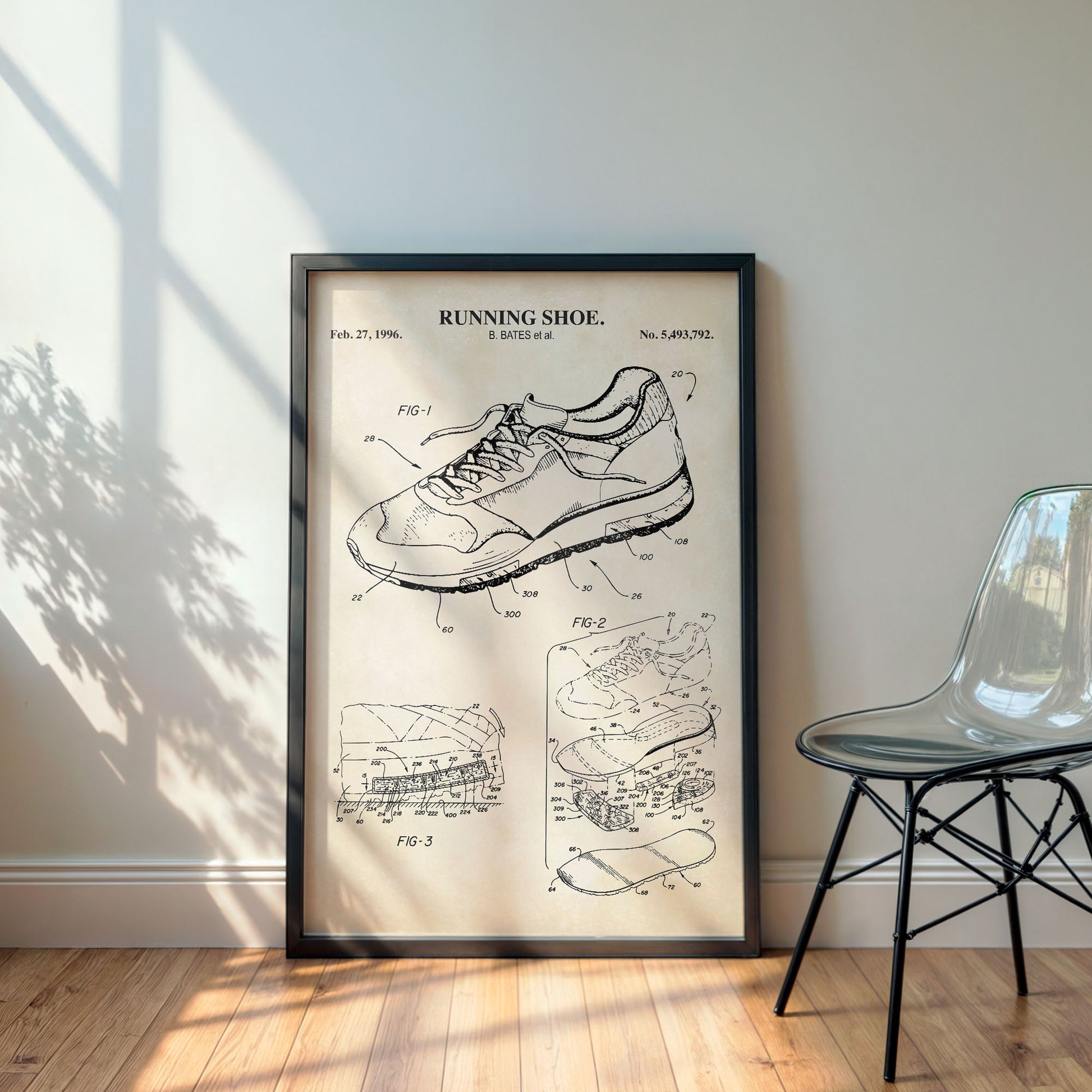 Framed poster of a running shoe patent on a wall with a chair and plant in the background