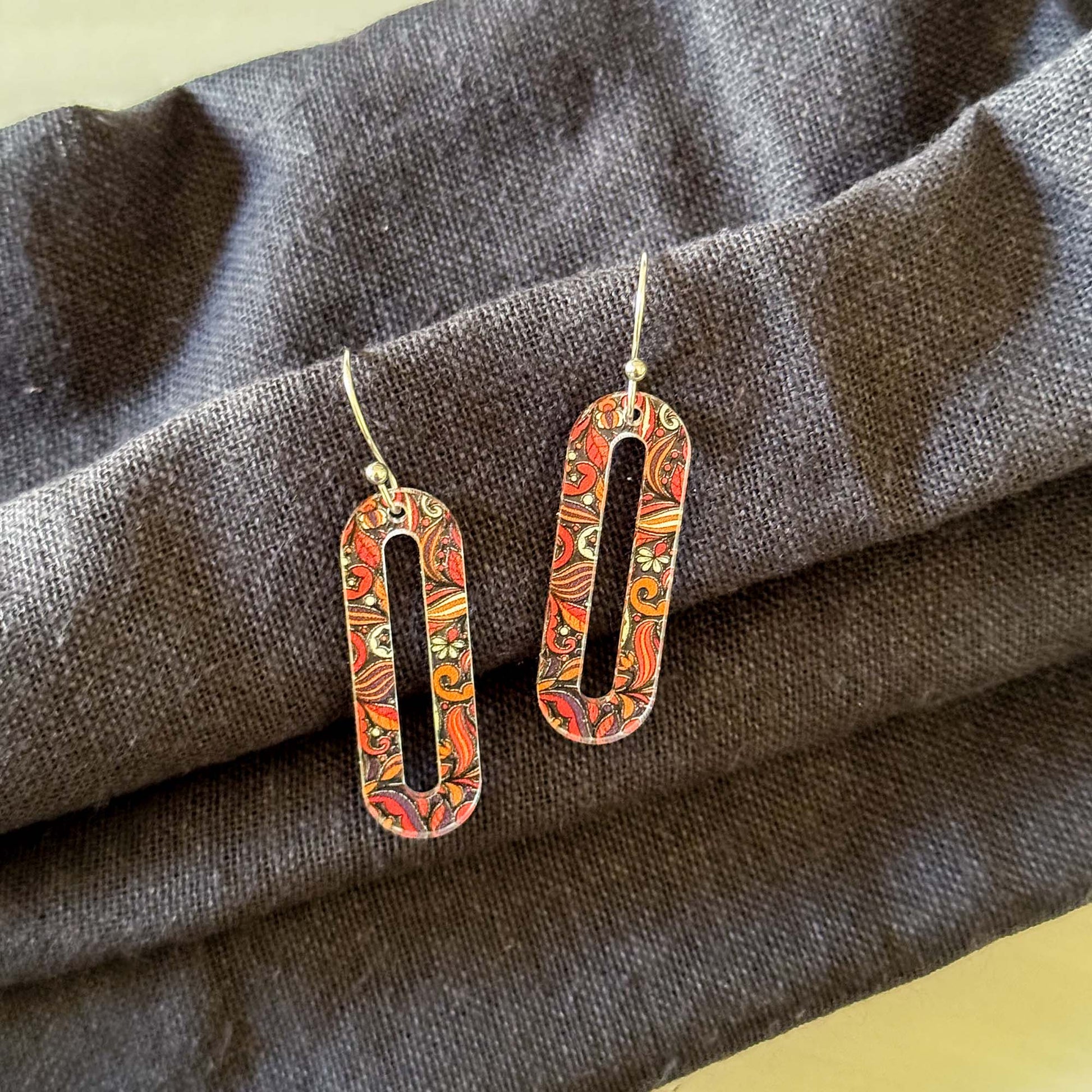 Pair of floral-patterned earrings on a gray fabric background
