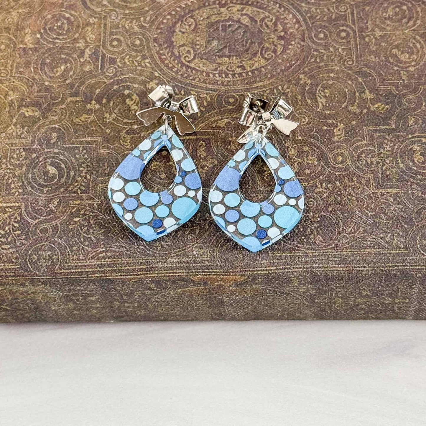 Pair of blue patterned earrings on a textured brown surface