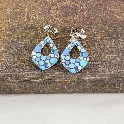 Pair of blue patterned earrings on a textured brown surface