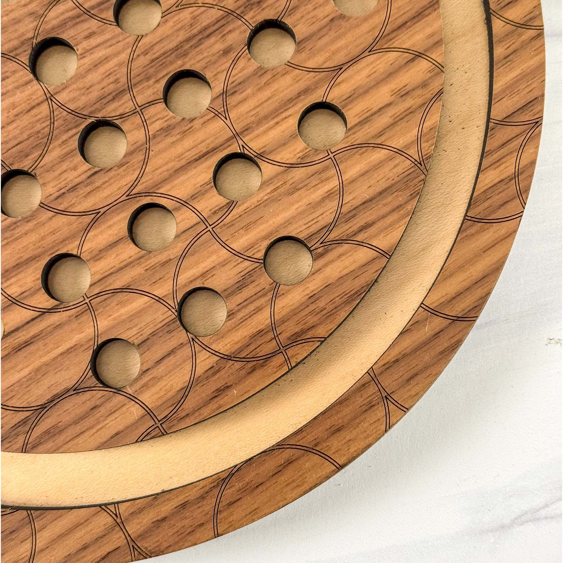 Close up of a wooden marble solitaire game that has a circular pattern on a white background