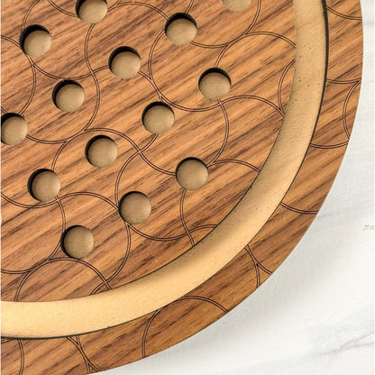 Close up of a wooden marble solitaire game that has a circular pattern on a white background