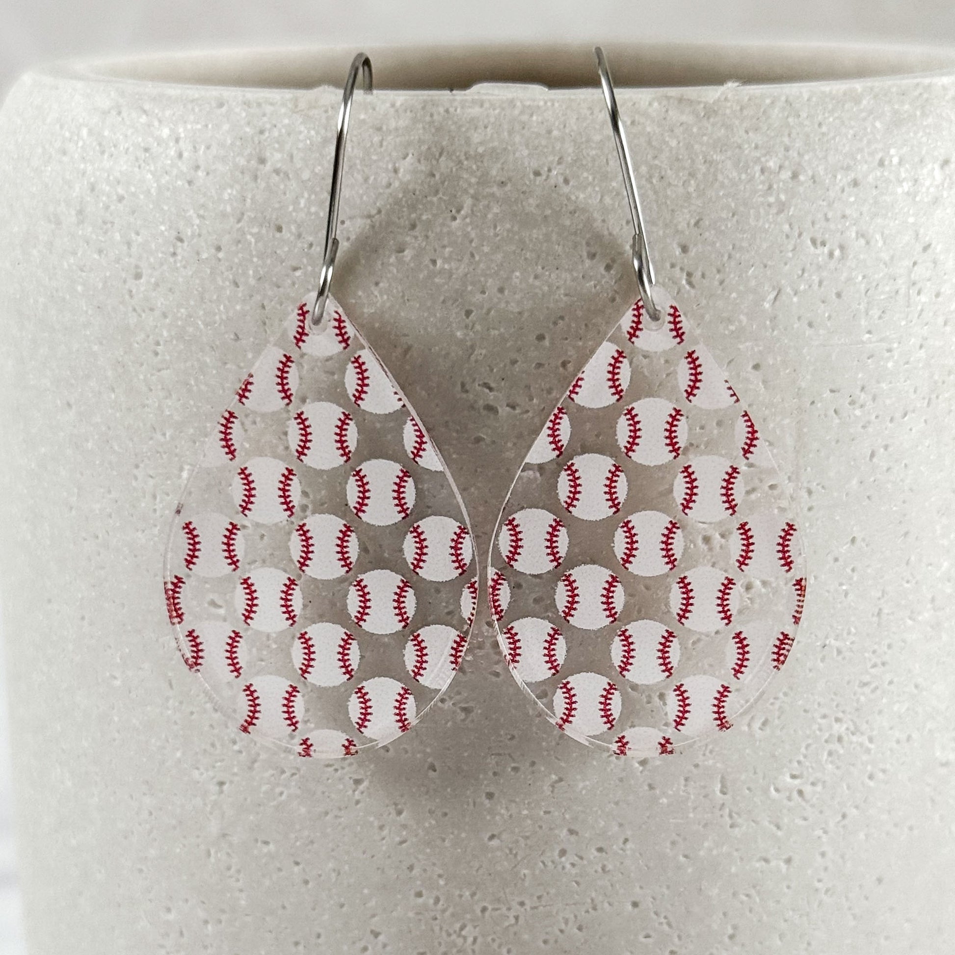 Teardrop-shaped earrings with baseball pattern on a white background
