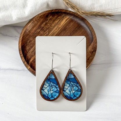 Teardrop-shaped blue mosaic earrings on a white card with a wooden base.
