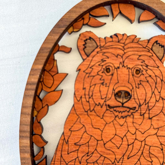 Close-up of detailed bear engraving and layered wooden woodland design