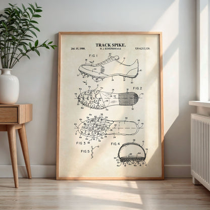 Framed patent poster of a track spike on a wall in a room with a plant and wooden side table.
