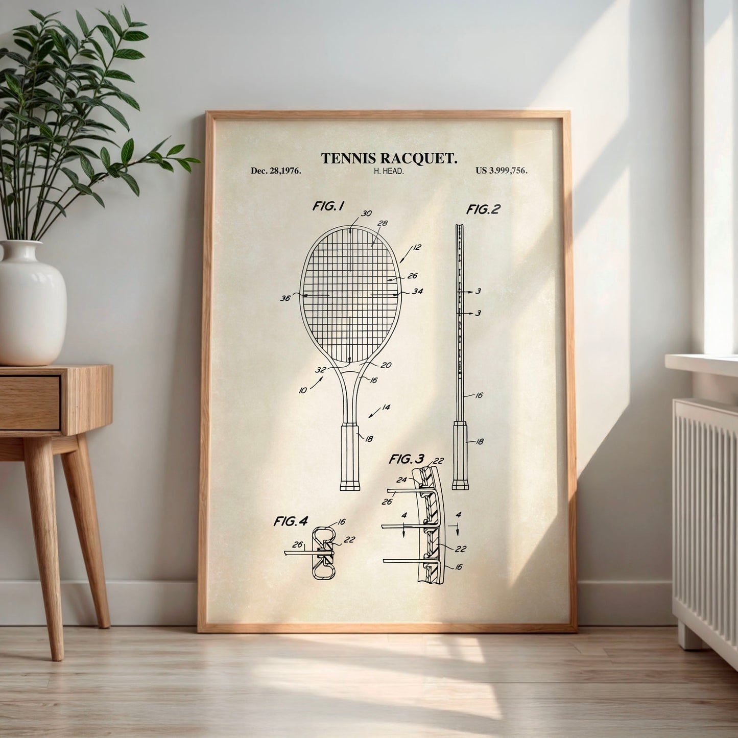 Framed tennis racquet patent print on a wall in a room with a plant and wooden side table.
