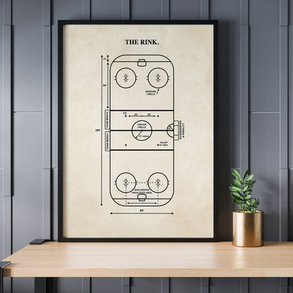 Framed diagram of a hockey rink on a wall above a wooden table with a plant.