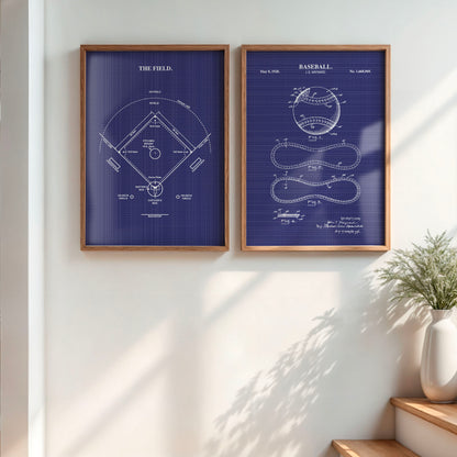 Two framed baseball-themed blueprint wall art prints hang on a white wall in a styled interior. The left print shows a white field diagram on a dark blue background, and the right print shows a baseball patent drawing on the same blue background.