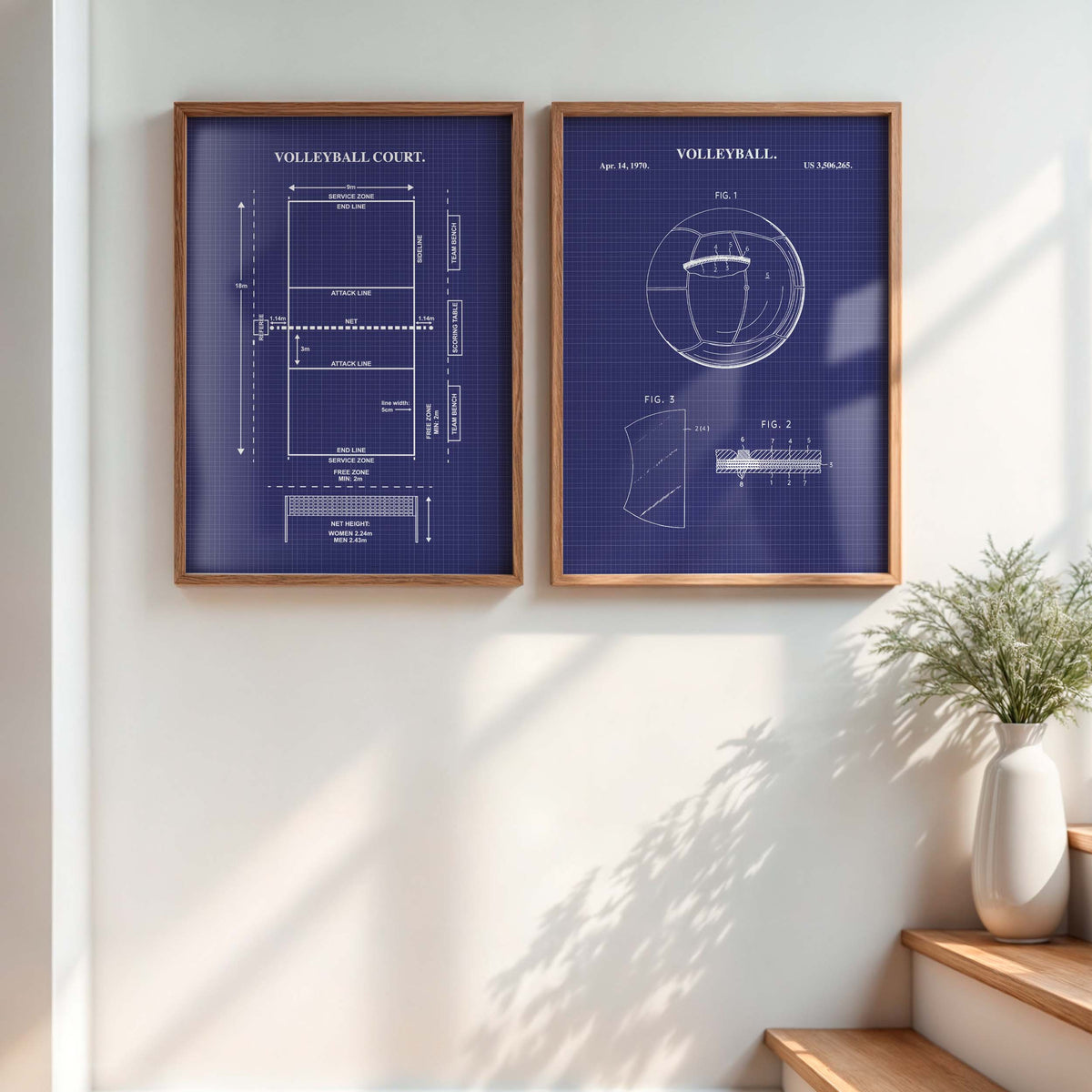 Two framed blueprint-style wall art prints hang on a white wall in a sunlit room. The prints have a dark blue background with white technical drawings and text reading VOLLEYBALL, with one showing a court layout and the other a volleyball patent-style diagram.