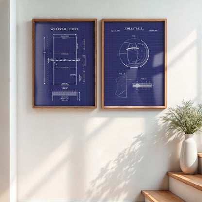Two framed blueprint-style wall art prints hang on a white wall in a sunlit room. The prints have a dark blue background with white technical drawings and text reading VOLLEYBALL, with one showing a court layout and the other a volleyball patent-style diagram.