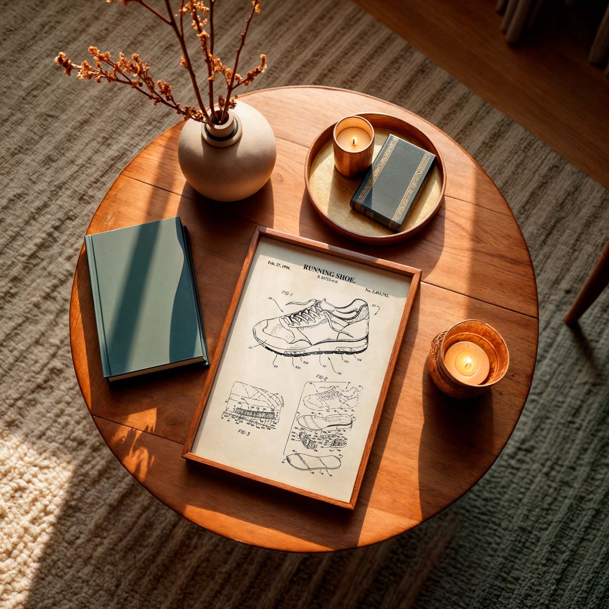 Wooden coffee table with a running shoe design blueprint, candles, and books on a carpeted floor.
