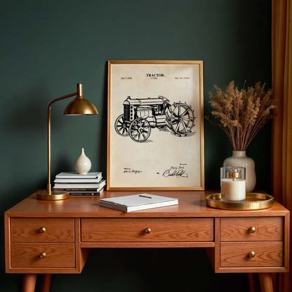 Wooden desk with framed tractor blueprint, lamp, books, and decorative items against a dark green wall.
