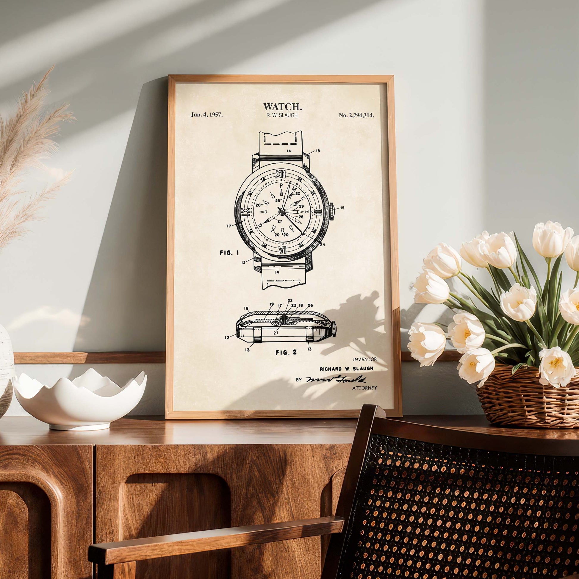 Framed watch patent print on a wooden surface with flowers and decor.