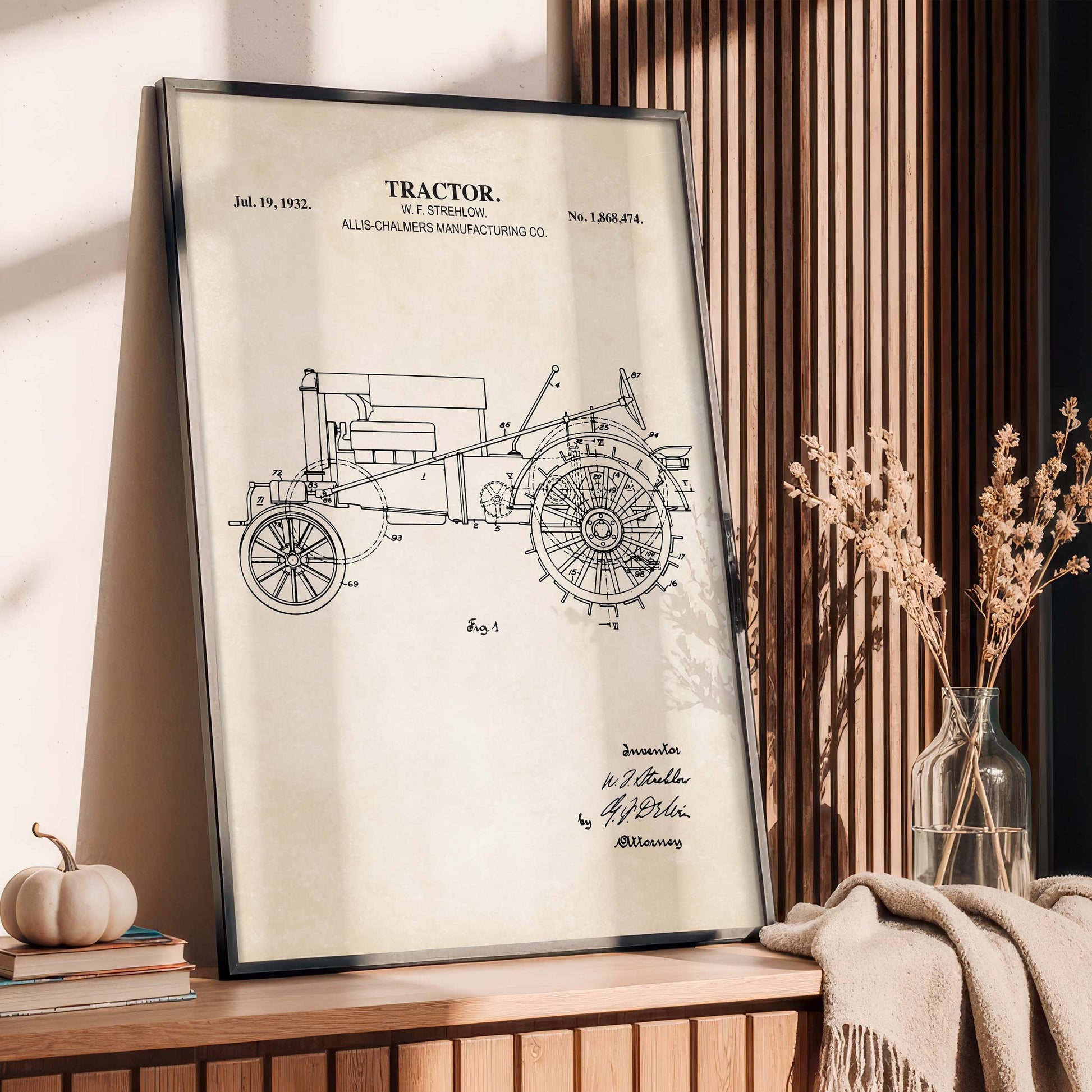 Framed tractor blueprint on a wooden surface with decorative items.